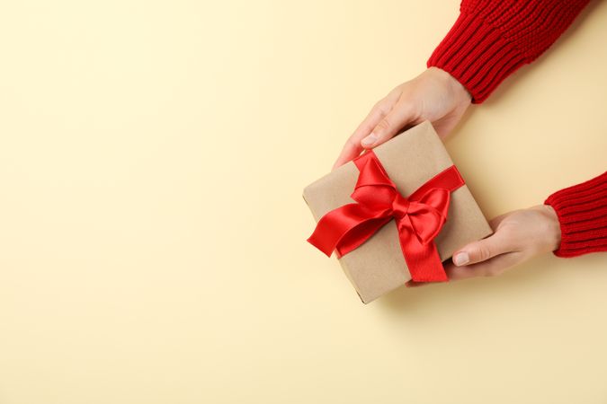 Young woman holding gift box on color background, space for text