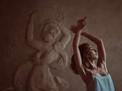 Woman with raised arms copying pose of female on relief