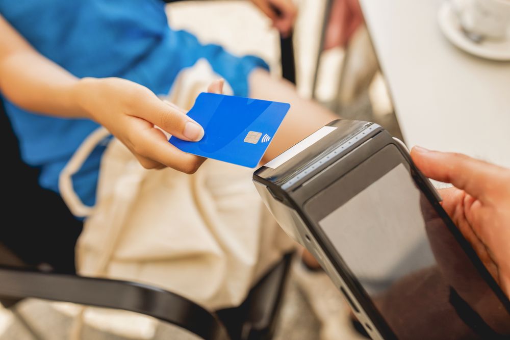 A person pays with a contactless credit card on a pos payment terminal after having a coffee