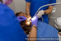A Black female patient with dental hygienist checking gums and teeth 0Ldd6V