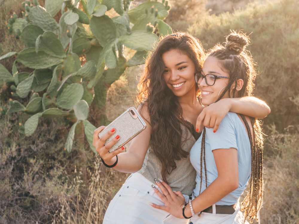 Smiling trendy young women taking selfie at countryside
