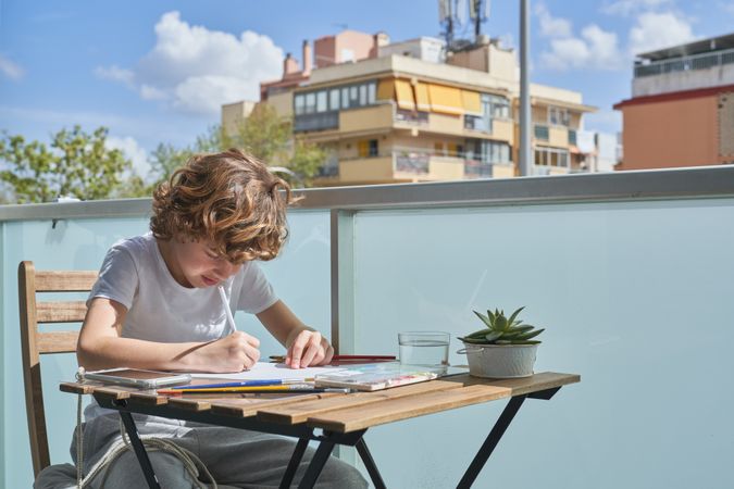 Focused boy painting on terrace