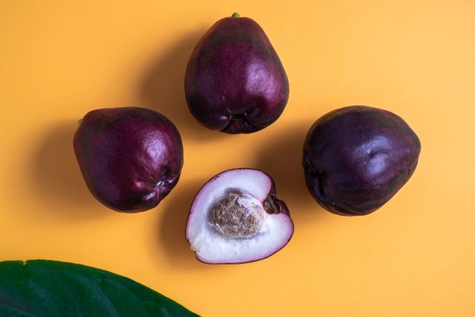 Four Syzygium malaccense or known as jambu jamaika fruits are on a yellow background