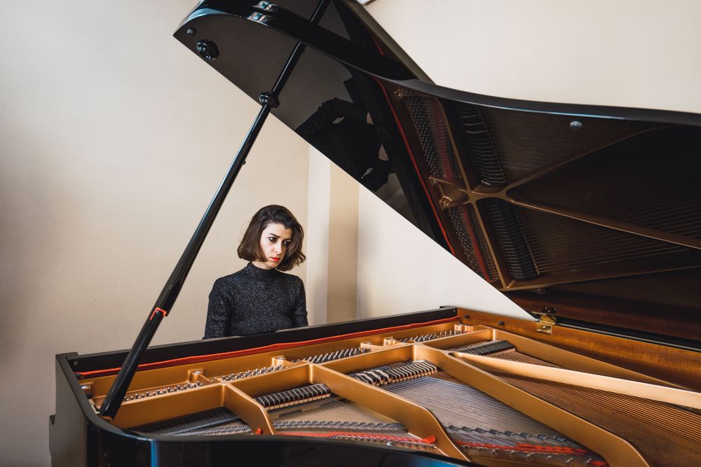 Young woman playing notes behind a piano