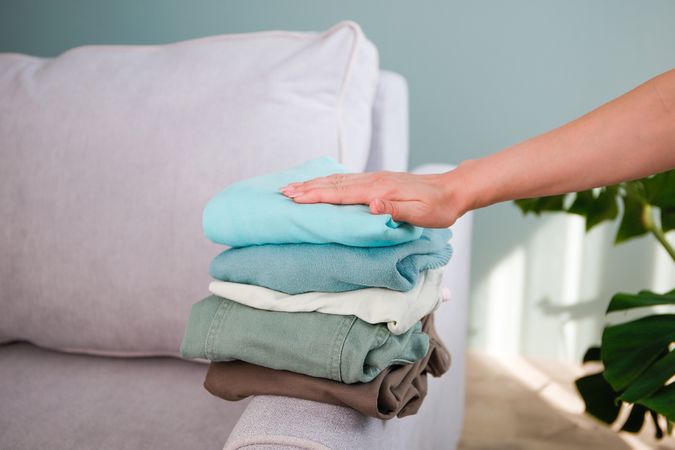 Pile of colorful warm clothes on the grey sofa.