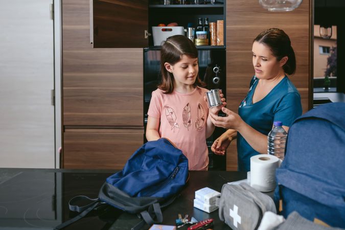 Mother preparing emergency backpack with her daughter