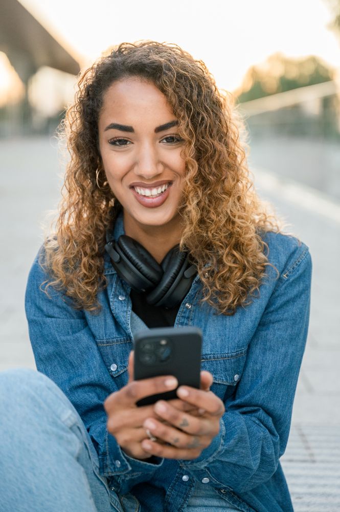 Smiling woman with smartphone on street