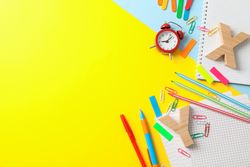 Flat lay composition with school supplies on two tone background, space for text