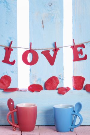 Cups with spoons and the word love hung on a blue fence
