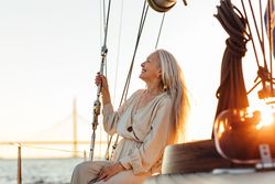 Content woman sitting on a sailboat at sunset