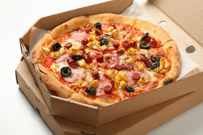 Tasty pizza in carton box on plain background