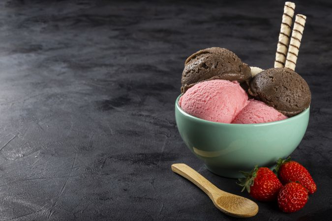 Bowl with Neapolitan ice cream on dark background.