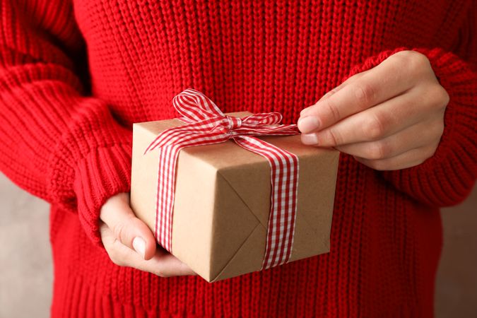 Young woman holding gift box with bow, close up