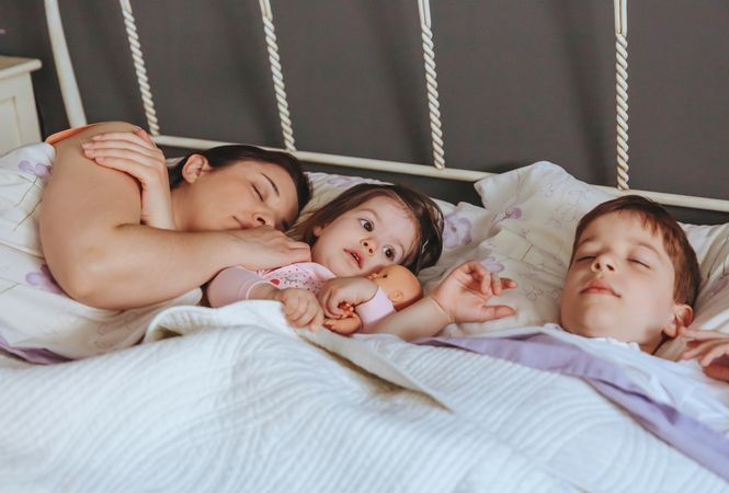 Mother sleeping with young son and daughter