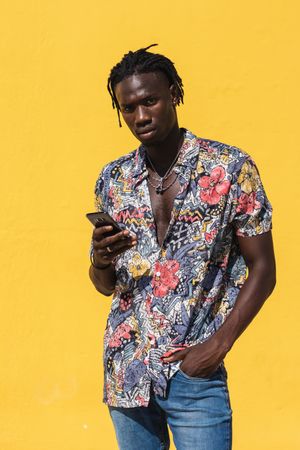 Stylish Black man in colorful shirt with smartphone