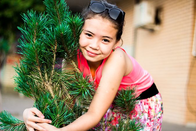 Young girl hugging small pine tree outdoor