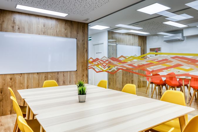 Interior of light modern office with colorful furniture against big window