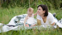 Pleasant mother and baby lying on blanket on picnic in field