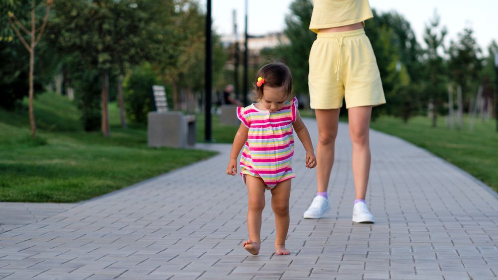 Toddler girl and mother walking on path