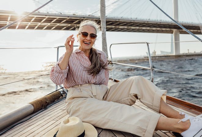 Stylish mature woman lounging on a yacht bow wearing sunglasses