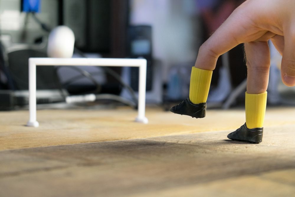 Hand playing football on a desk