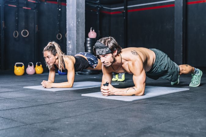 Muscular fellows doing abs in contemporary health club