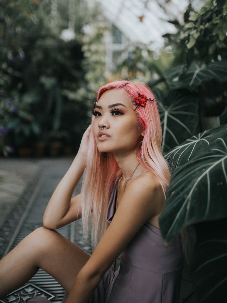 Woman with pink hair sitting among trees