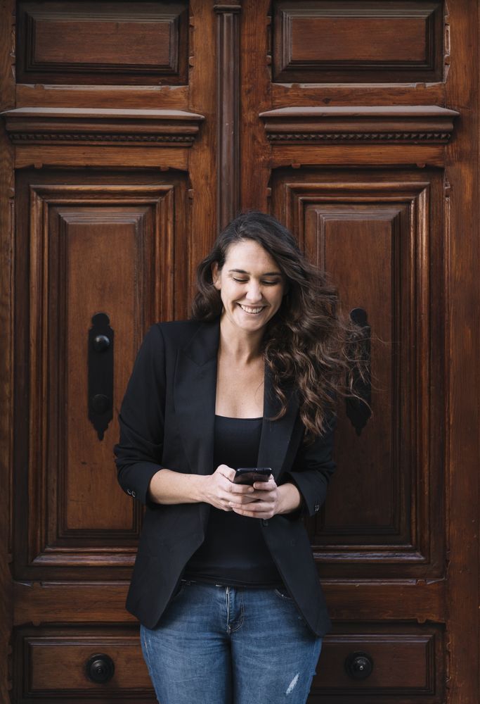 Young female using mobile phone on wooden door