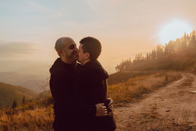 Men hugging and kissing in forest