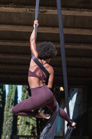 Slim woman doing yoga with aerial silks in city