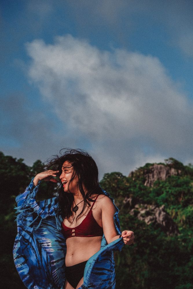 Smiling woman in red bikini and blue shirt standing outdoor