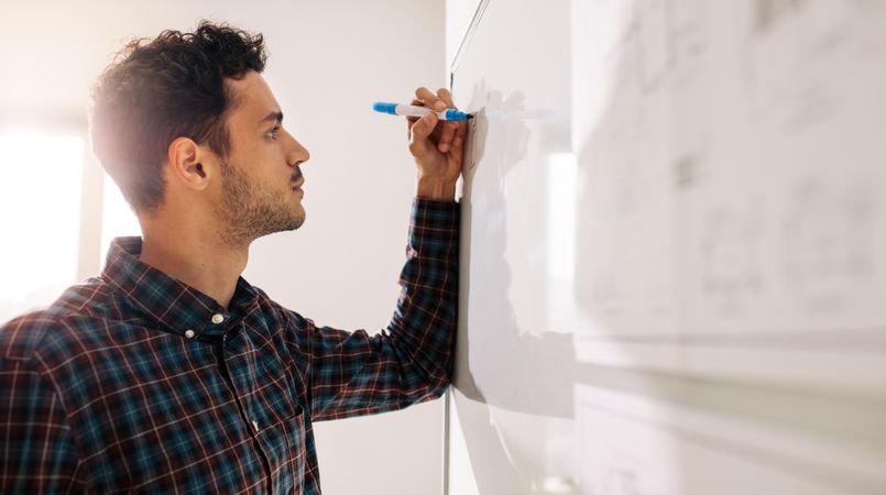 Male professional writing on dry erase board using a marker pen