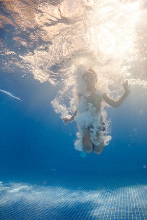 Small boy swimming in bubbling water in pool