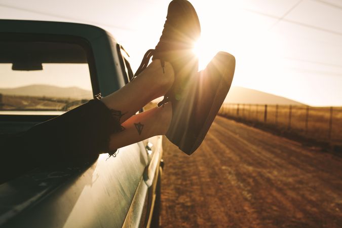 Woman’s legs with tattoos crossed and hanging over pickup truck