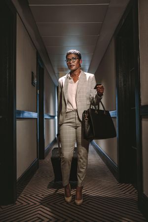 Businesswoman walking in hotel corridor with luggage