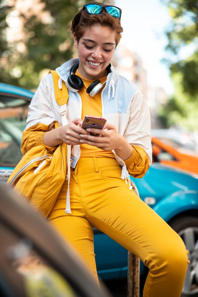 Stylish young woman using smartphone on street in downtown