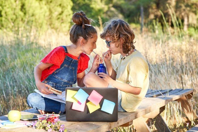 Happy kids drinking beverage from bottle together