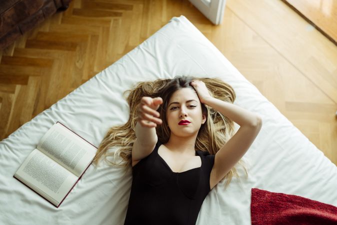 Young confident woman on bed pointing at camera