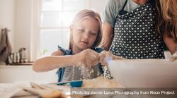 Young girl cooking with flour in the kitchen with her mother 4dQGdb