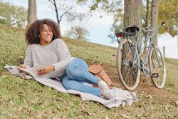 Happy Black Latina female reading book in nature