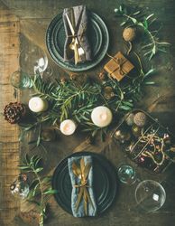 Festival holiday table setting on wooden table, with gold ornaments and branches