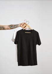 Arm holding two t-shirts on hanger