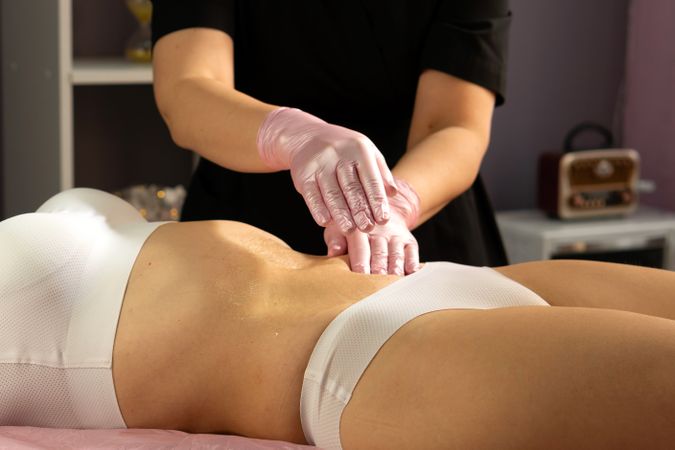 Therapist performing abdominal massage during honey body treatment.