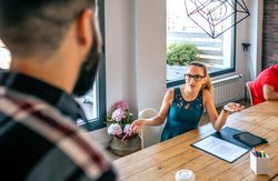 Happy woman talking with unrecognizable man in coworking office