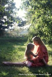 Little girl sitting on her mother's lap out in nature 5nm3m0