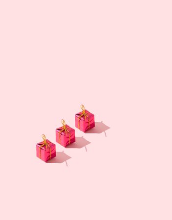 Three red presents on pink background