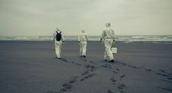 People with bacteriological protection suits walking on the beach