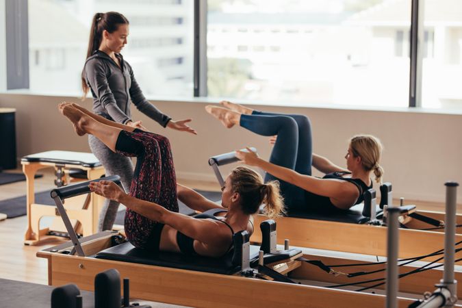 Two fitness women being trained by a pilates instructor