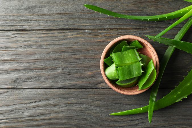 Aloe vera leaves and slices on wooden table, space for text and top view. Natural treatment