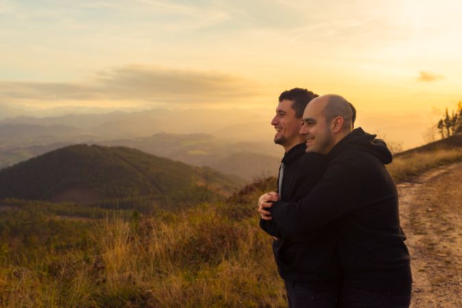 Men hugging on road on hill